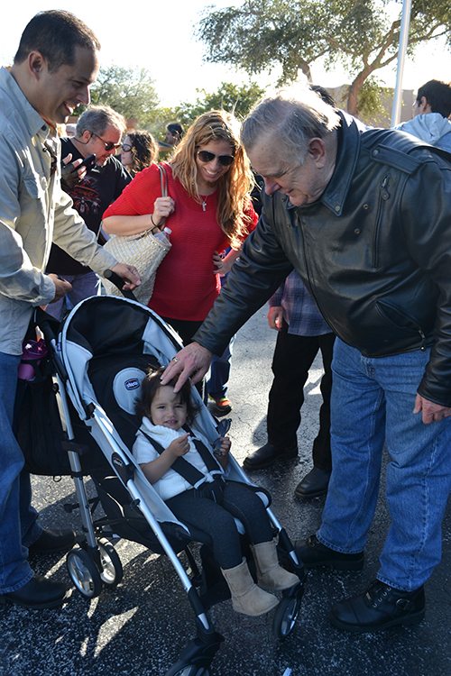 Archbishop Thomas Wenski blesses 18-month-old Alexandra Cuevas, who received her first blessing from him when she was in her mother's womb, at the first Poker Run.