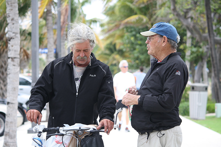 St. Paul  Street Evangelization member, Fred Ford, ministers to a tearful cyclist, who shared that he is out of work and is now homeless. He graciously accepted a rosary and asked for prayer.