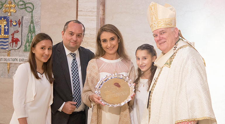 Archbishop Thomas Wenski presents the One in Charity award to the Martinez family of Our Lady of Guadalupe Church in Doral. From left: daughter AnaPaula, 14, dad Carlos, mom Citlaly and daughter Renata, 12. The One in Faith, One in Hope and One in Charity awards were presented at the annual Thanks-for-Giving Mass for archdiocesan donors, Nov. 20 at St. Mary Cathedral.
