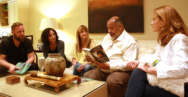 Flourish 2017 coordinators, from left, Corey Haese, Adriana Gonzalez, Laura Haese, Joseph King, and Victoria Meyer listen as King reads from conference speaker Rifqa Bary’s book, “Hiding in the Light,” during a recent meeting at Meyer's home.