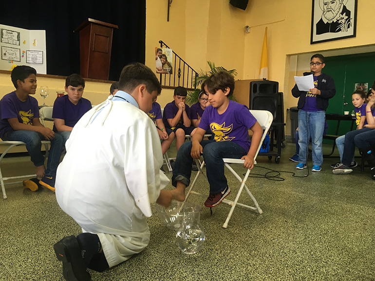 Jesus ( Eduardo Infante) humbly washes a third grader's foot.