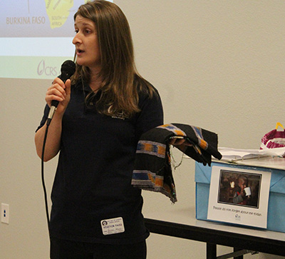 Rachel Holmes, a representative from Catholic Relief Services, shows students from Our Lady of Lourdes School sample fabric that is being made by women in Burkina Faso, Africa. The school and community partnered with CRS and Rise Against Hunger to pack 50,000 meals for Africa.
