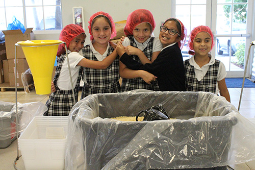 Hold on, things are about to get messy: Third graders from Our Lady of Lourdes prepare for food packing instructions.