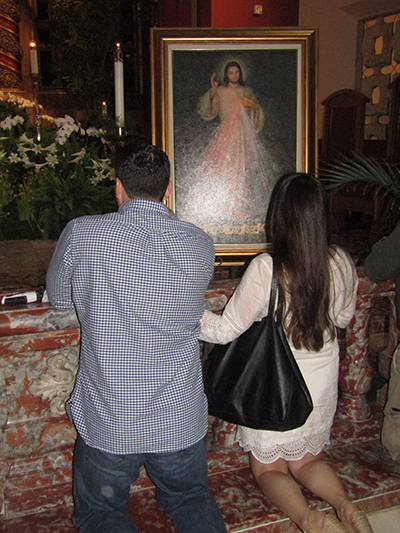 Vanessa and Alex Arvesu pray in front of an image of Divine Mercy after the second annual Infertility Mass at Little Flower Parish, Coral Gables, April 23. The start of National Infertility Awareness Week this year coincided with the second Sunday of Easter, feast of Divine Mercy.