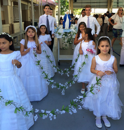 Second graders from St. Bonaventure School, wearing their first Communion dresses and carrying garlands of flowers, lead the procession in honor of Mary.