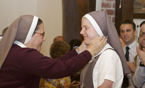 Después de vestirse con el hábito completo, la Hna. Molly Joyce del Corazón Misericordioso de Jesús recibe un crucifijo de la Hna. Ana Margarita Lanzas.