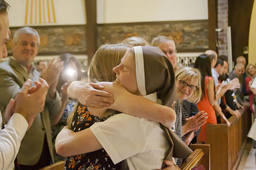 Después de vestirse con el hábito completo, la Hna. Molly Joyce del Corazón Misericordioso de Jesús abraza a un miembro de su familia.