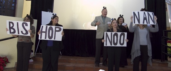 Employees prepare greet Bishop Noonan with a revised version of the Mickey Mouse song.