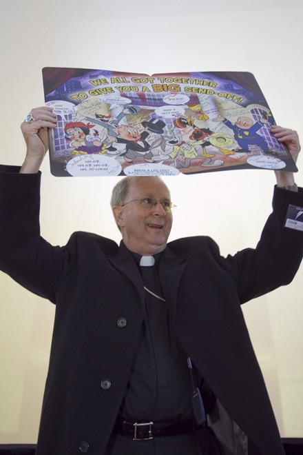 Bishop Noonan holds up one of the two goodbye cards signed by Pastoral Center employees.
