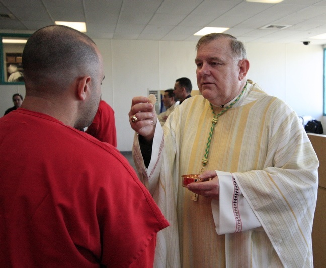 Archbishop Wenski gives communion to a detainee, one of many men being held at Krome from various countries including: Central and South America, the Caribbean, and Africa.
