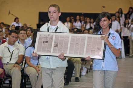 Sophomores Alejandro Hernandez and Elexa Suarez carry a framed copy of the Nov. 1, 1963 edition of the Pace High School newspaper, Kerygma, during the offertory procession.
