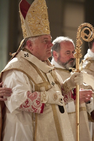 Archbishop Thomas Wenski pauses at the altar while wearing a more ornate miter, his pallium and gloves to begin the celebration of Mass.