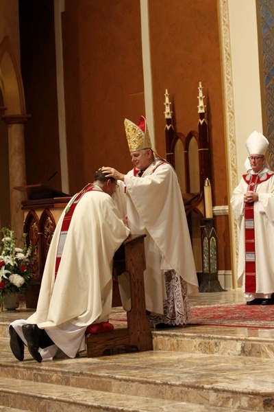 Archbishop Thomas Wenski lays hands on Bishop Gregory Parkes, during the rite of ordination of a bishop.