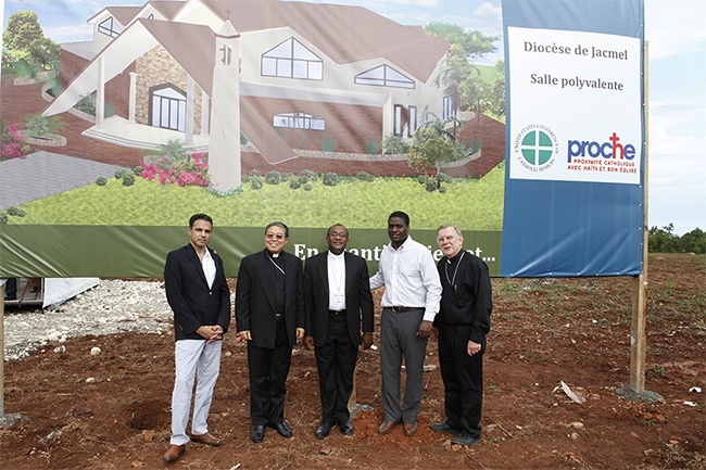 Posing in front of the architect's rendering of the new multipurpose building in Jacmel, from left: Jacques Liautaud, the U.S. bishops' manager for Haiti, Archbishop Bernardito Auza, papal nuncio to Haiti, Bishop Launay Saturné of Jacmel, Stephan Destin, director general of PROCHE in Haiti, and Archbishop Thomas Wenski.