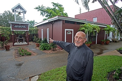 Father Roger Holoubek stands outside the St. Maurice Church complex, formerly Smith's Stables when the parish was founded in 1970.
