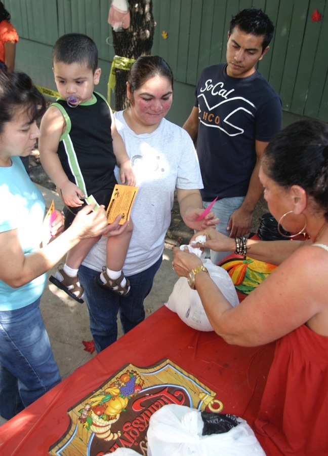 Maria Machado and her son, Roberto Machado, 2, receive a turkey from Norma Jean Abraham of the Anthony Abraham Foundation.