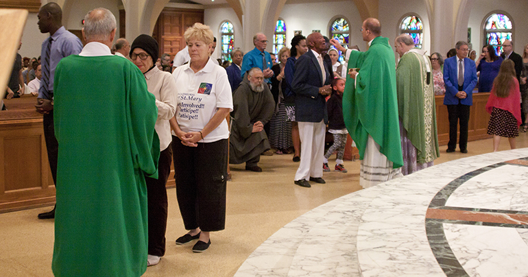 Archbishop Thomas Wenski and Father Christopher Marino, rector of St. Mary Cathedral, distribute the Eucharist to those in attendance at the Mass marking the first anniversary of the closing of the Second General Synod of the Archdiocese of Miami.