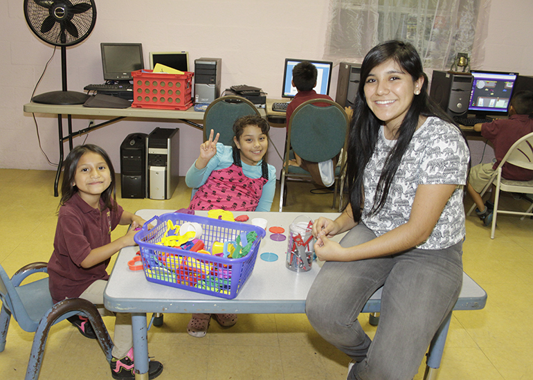 Karla Andrade, voluntaria de México ayuda con sus tareas a niños que asisten al programa de después de clases.  A su derecha Diana Sandoval de 8 años e Islen Calderón de 6 años.
