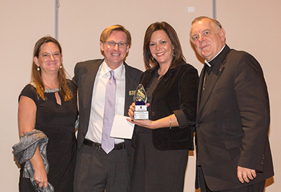 Angie Chirino, third from left, accepts a New American Award on behalf of her father Willy Chirino, singer and Pedro Pan immigrant. Posing with her are, from left, Mary Kramer, president of the Catholic Legal Services board, Randy McGrorty, the agency's CEO, and Archbishop Thomas Wenski.