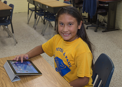 Jasmine Gago sits at her desk with her iPad in her fourth grade classroom at Sts. Peter and Paul. Jasmine is a recipient of the Step Up scholarship.
