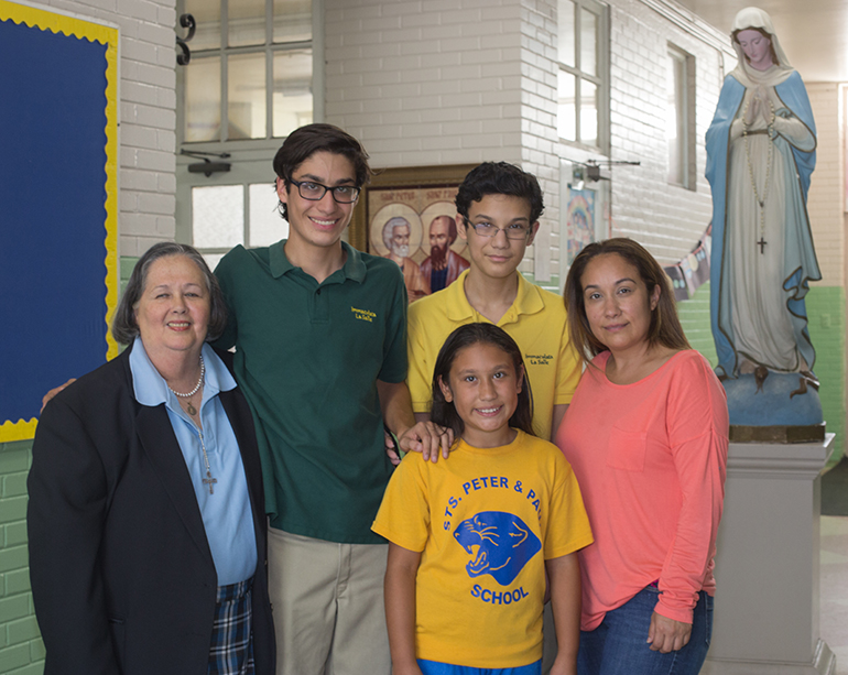Carlota Morales, left, principal of Sts. Peter and Paul School in Miami, poses with Jason, Jasmine, Justin, and Yvonne Gago before a statue of the Virgin Mary at the school. All three siblings benefit from the Step Up scholarship program.
