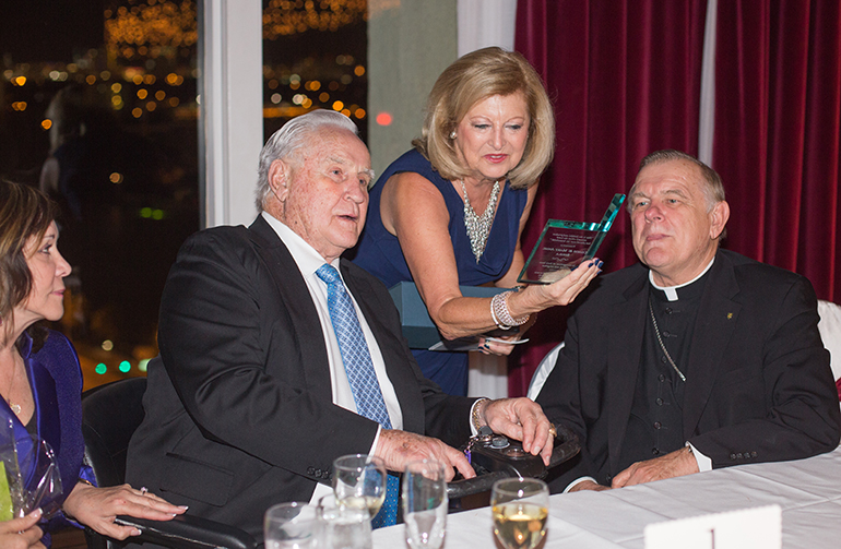 Danoushka Capponi, chairperson of the committee that organizes St. Joseph Church's annual gala, presents a plaque of appreciation to the guests of honor, former NFL Coach Don Shula and his wife, Mary Anne, as Miami Archbishop Thomas Wenski looks on.