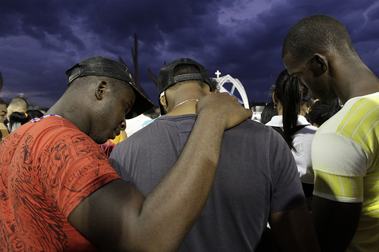 In this March 2012 photo, three young men from Santiago huddle close to follow Pope Benedict's Mass on the booklets distributed by the Cuban Church. The Church played a crucial role in facilitating the Dec. 17 agreement to re-establish diplomatic relations between the U.S. and Cuba.