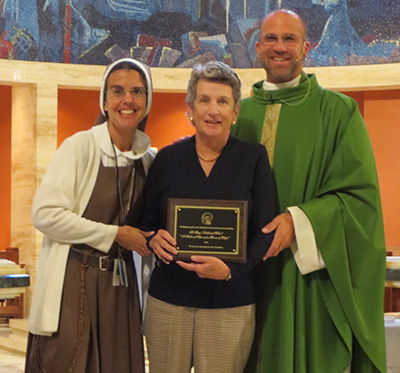 La Hermana Michelle Fernández y el P. Christopher Marino posan con Susan Abell. En septiembre, Abell caminó el Camino de Santiago para recaudar $ 10,000 para la Escuela St. Mary Cathedral.