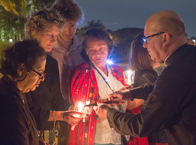 Father Michael Davis, pastor of Little Flower in Coral Gables, lights candles for those who attended the blessing ceremony for the life-size nativity scene on display outside the church.