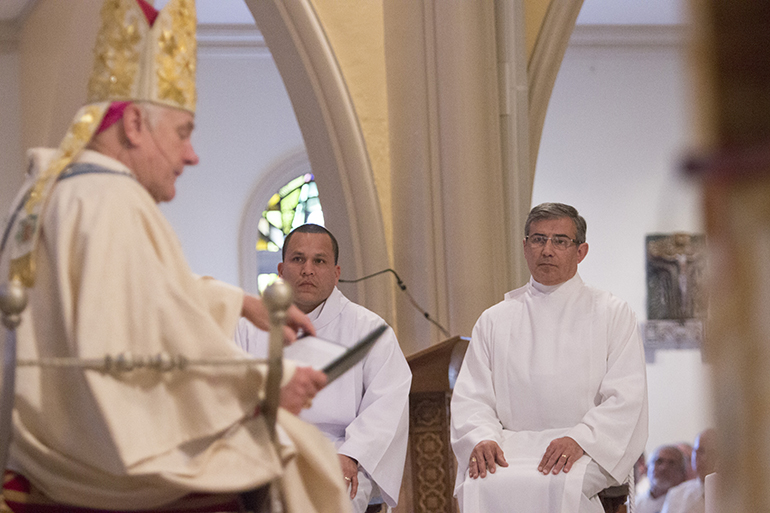 Ordination candidates Alfredo Valle and Jose Antonio Santos listen to Archbishop Thomas Wenski's homily.