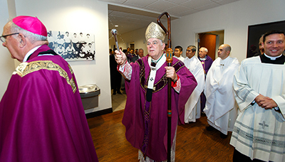 Archbishop Thomas Wenski sprinkles holy water along the hallways of the new seminary dormitory building.