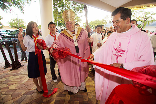 Father Joseph Long Nguyen, administrator, and Archbishop Thomas Wenski cut the ribbon marking the dedication of Our Lady of La Vang Vietnamese Mission's new church home, on the site of the old St. Charles Borromeo Church in Hallandale Beach.