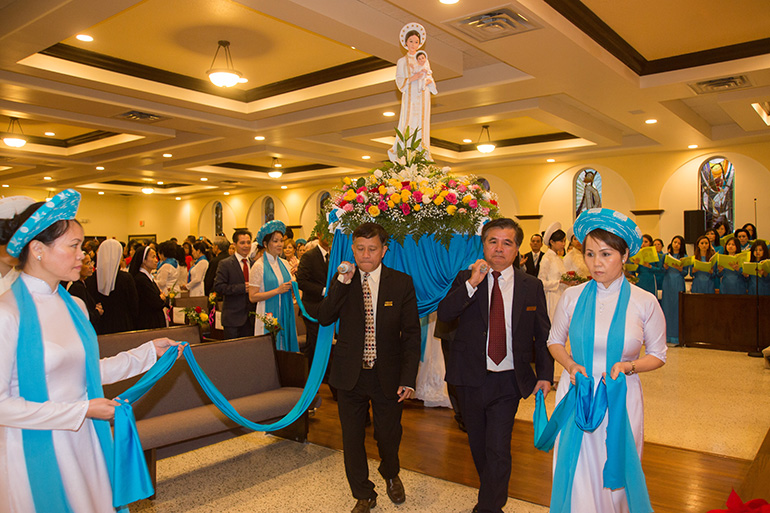 Vietnamese Catholics carry an image of their patroness, Our Lady of La Vang, into their new church home at the start of the dedication Mass.