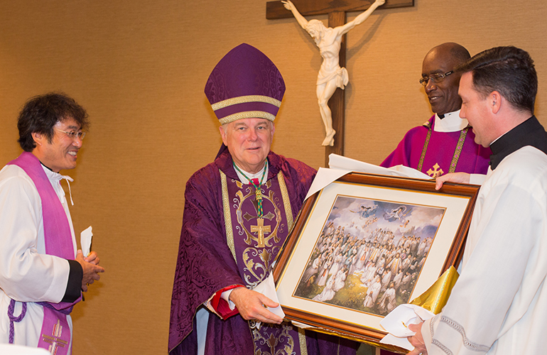 Archbishop Thomas Wenski receives a gift from South Florida's Korean community: a framed picture of 103 Korean martyrs canonized by Pope John Paul II in 1984. At left is Father Bongmoon Lee, at right are Msgr. Jean Pierre, director of the Ministry to Cultural Groups, and Father Richard Vigoa, priest-secretary to the archbishop.