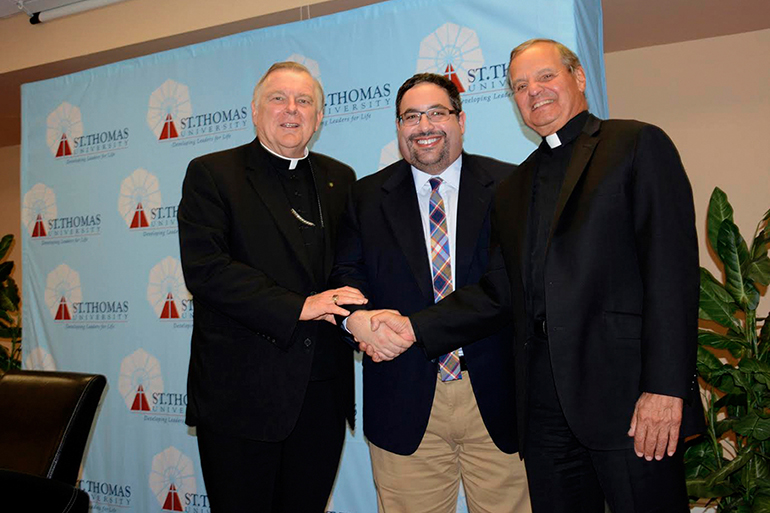 Archbishop Thomas Wenski and St. Thomas University's president, Msgr. Franklyn Casale pose with Gary Goldbloom, a member of the university's board of trustees who donated _#### million to endow a chair in cybersecurity in the School of Business.