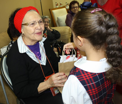 A St. Brendan Elementary student presents a Senior Center client with a Christmas gift.