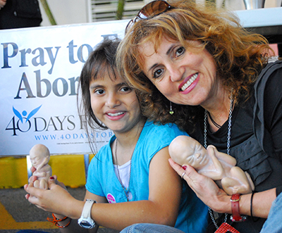 Liliana Simko and her daughter Isabella, 8, hold in-utero replicas of unborn babies.