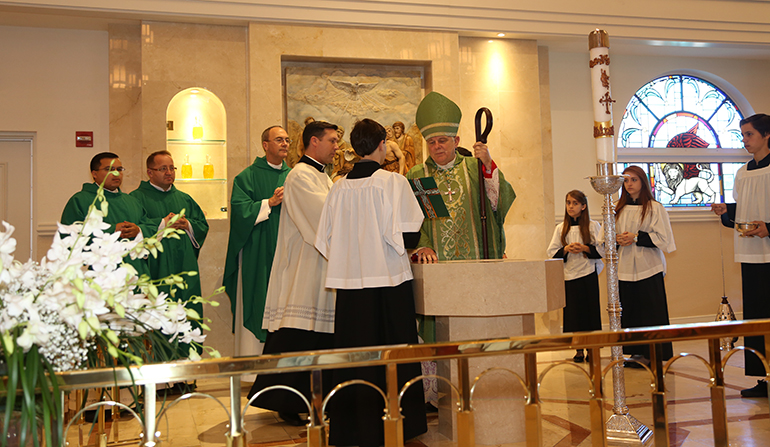 Archbishop Thomas Wenski blesses the new baptistery at Our Lady of Lourdes Church as Msgr. Kenneth Schwanger, pastor, and Fathers Andrew A. Pietrasko and Elvis Gonzalez, parochial vicars, look on.