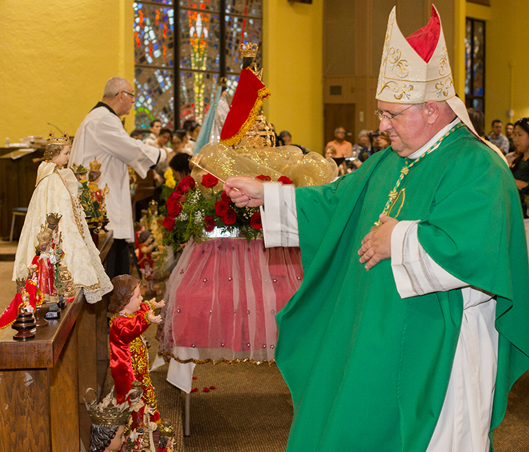 Auxiliary Bishop Peter Baldacchino blesses statues of Senor Santo Nino lined up on altar rail of St. Bernard Church.