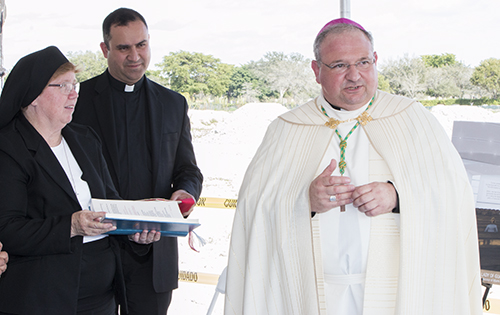 Auxiliary Bishop Peter Baldacchino speaks before blessing the ground where the church of Our Lady of Guadalupe will be built. With him are Father Israel Mago, pastor, and Sister Elizabeth Worley, archdiocesan chancellor for administration.