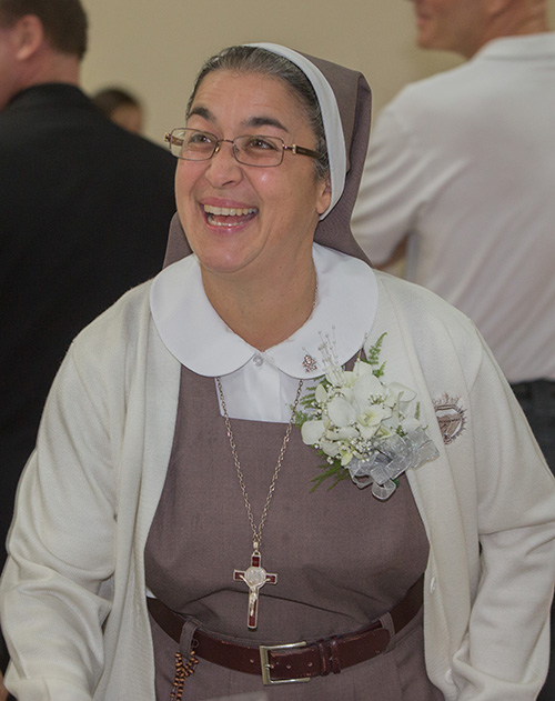 La Hermana María José Socías, de Las Siervas de los Corazones Traspasados de Jesús y María, que estaba celebrando 25 años, reacciona a la ovación que recibió al entrar a la sala de recepción después de la Misa.