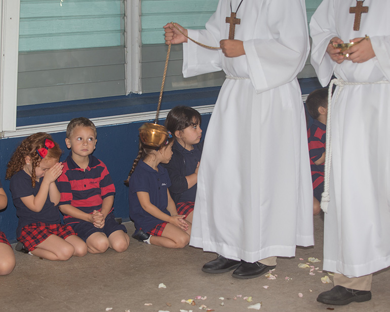 Pre-schooler Caterina Cueto, 4, prays as Nevan Morales, 4, watches the procession.