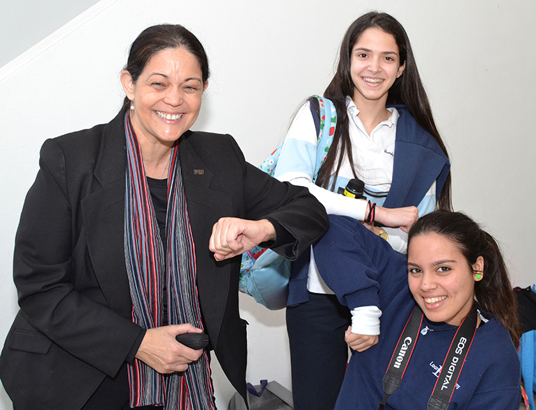 Dr. Aileen Marty shows junior Cassandra Garcia, center, and senior Alexandria Rodriguez how to greet someone in Africa: touching elbows instead of shaking hands.