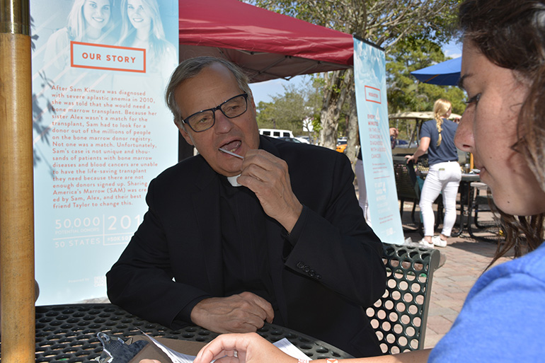 Msgr. Franklyn M. Casale, St. Thomas University's president, provides a swab sample to the organization Sharing Americaâ€™s Marrow (SAM). The swabs - more than 300 of them - came during a "Donor Jam" event spearheaded by St. Thomas' softball team. The samples were collected to identify potential bone marrow donors for 22-year-old Sam Kimura and thousands of other patients fighting blood cancer and other diseases.