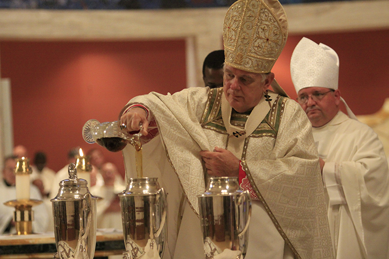 Archbishop Thomas Wenski pours balsam - which will add a perfumed aroma - into the oil of chrism.