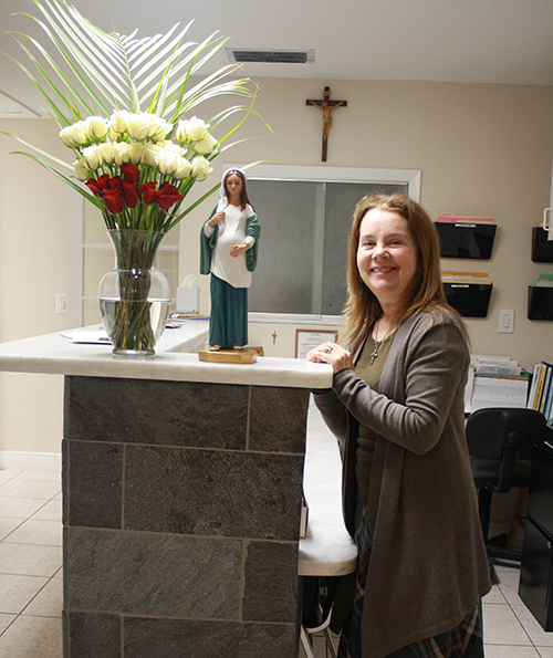 Kathy Weissinger, director of the South Dade Pregnancy Help Center, poses next to a statue of Our Lady of Hope Expectant, which depicts a pregnant Madonna.