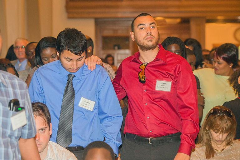 Sponsor Anthony Caballero places his hand on the shoulder of catechumen Christian Caballero of St. Martin de Porres Church in Leisure City.