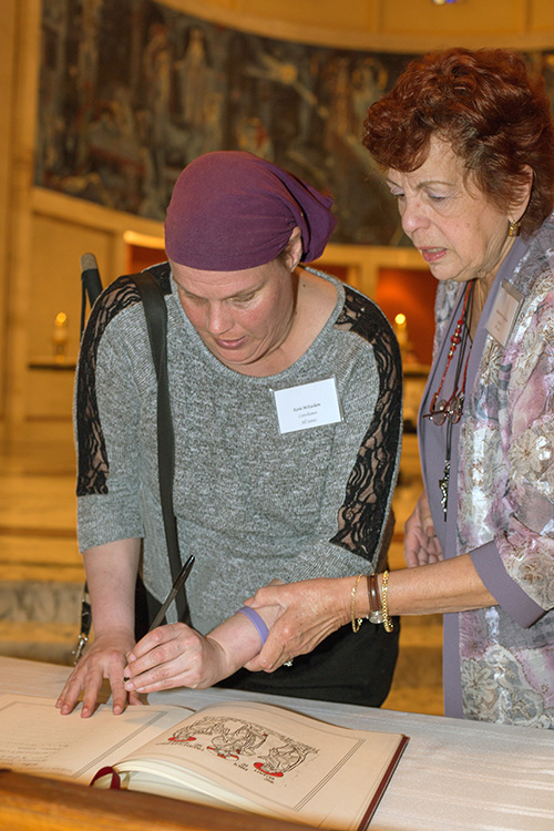 Katie McEachern, a catechumen from All Saints Church in Sunrise who is blind, signs the Book of the Elect with the help of her sponsor, Diane Perez de Alderete.