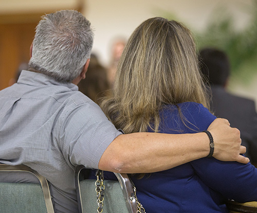 Michael Rodriguez wraps his arm around the shoulder of his wife, Jarnette, as they listen to speakers at Date Night.