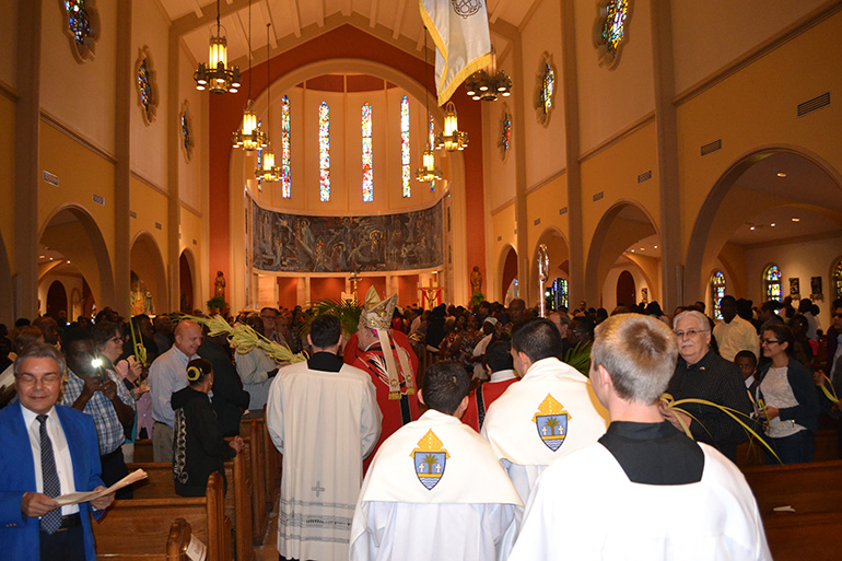 Followed by seminarians serving as acolytes, Archbishop Thomas Wenski processes into St. Mary Cathedral on Palm Sunday.